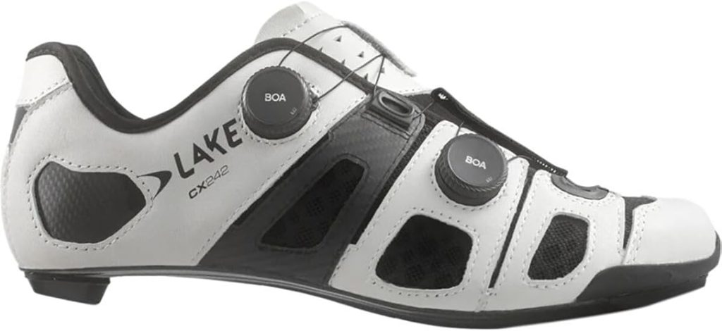 A side-profile studio shot of a white and black Lake CX242 road cycling shoe. The shoe is characterized by its "segmented" upper, consisting of six separate white Clarino leather panels held together by a black mesh framework. It features two black BOA Li2 dials and a thin, ultra-stiff carbon fiber outsole.